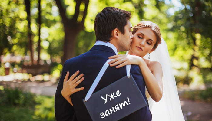 Жених и невеста за спиной табличка с надписью свадебная фотосессия
