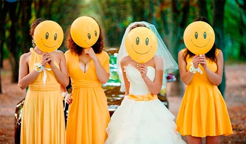 Невеста в белом и подруги в жёлтом платье закрывают лица шарами