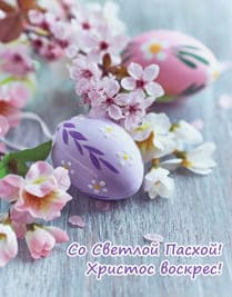 Цветы и пасхальные покрашенные яйца на деревянной поверхности