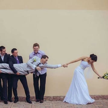 Невеста тянет жениха за руку, а его держат друзья 