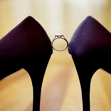 Обручальное кольцо между двумя туфельками фиолетового цвета   