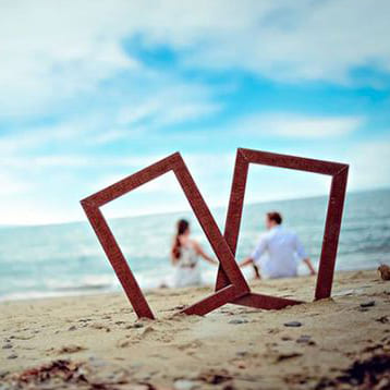 Рамки маленьких картин на пляже, а за ними молодая пара  