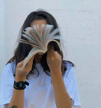 Фото на аву девушка листает книгу и скрывает лицо 