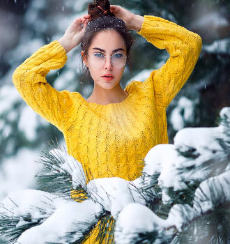 Девушка в жёлтом свитере  между деревьев в лесу 