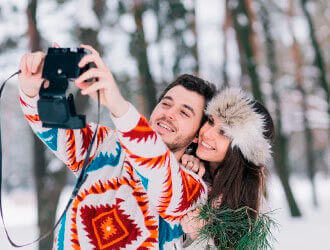 Зимняя фото в лесу девушка и парень фотографируются на фотик   