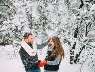 Зимняя фото в лесу девушка и парень падает снег с веток деревьев   